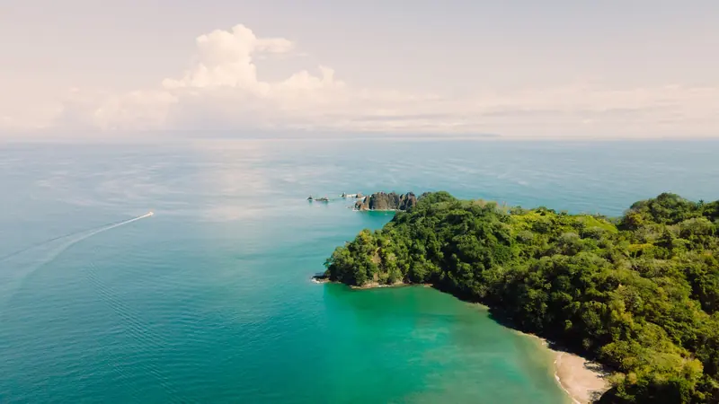 Aerial view of a jungle headland above a turquoise Costa Rican bay